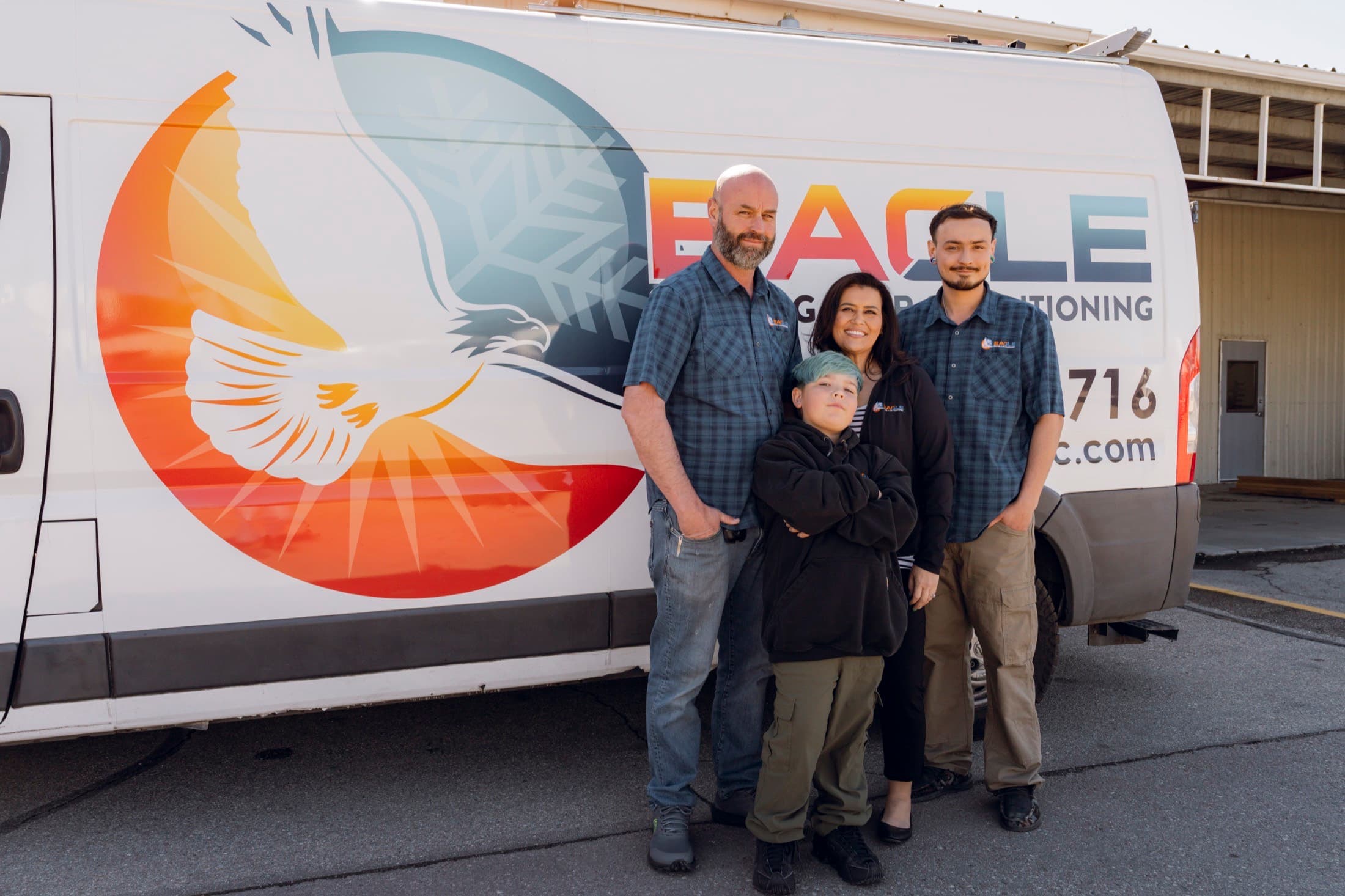 The Eagle Heating and Air family team in front of a branded service van