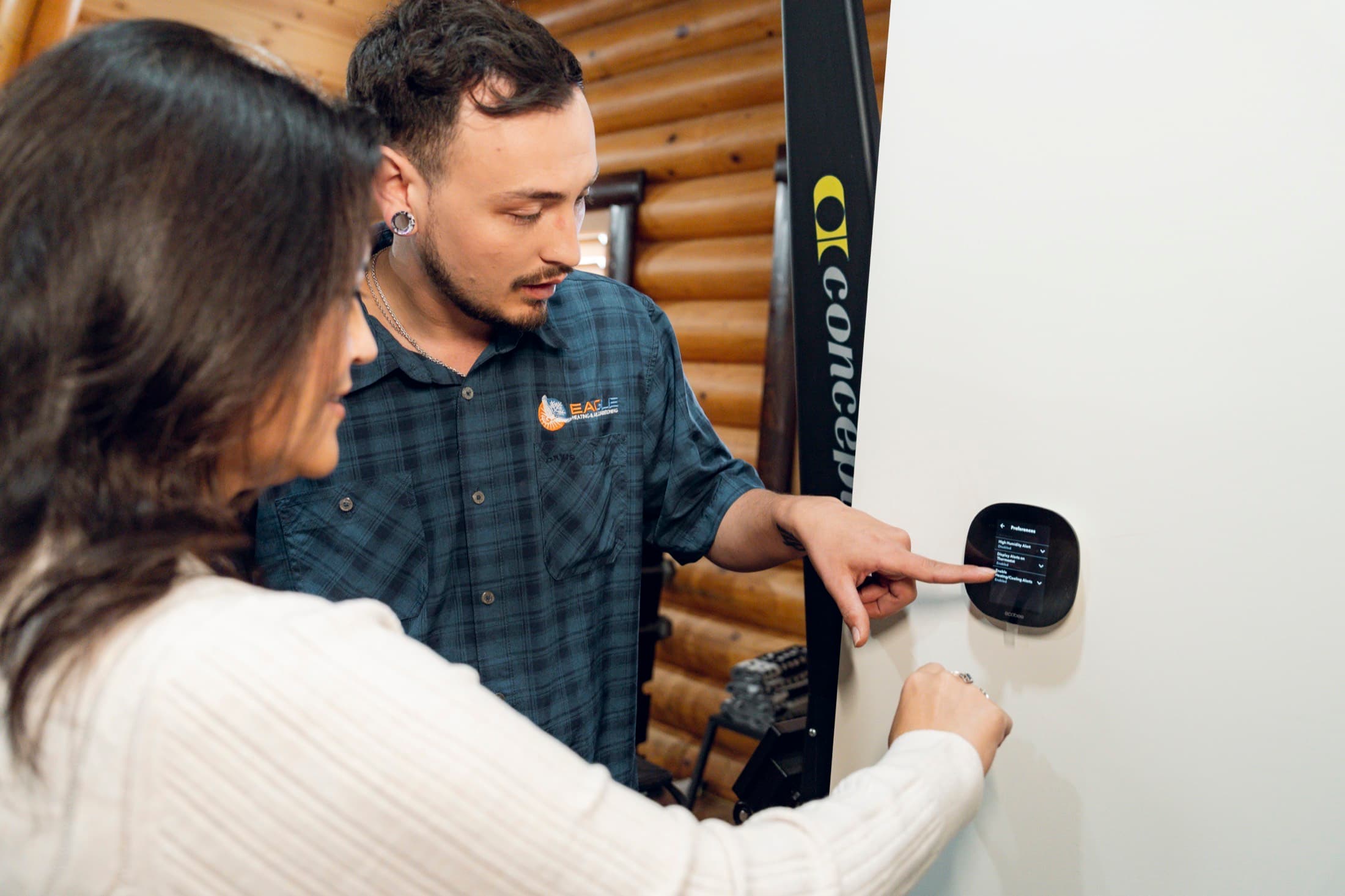 Eagle Heating and Air technician showing a homeowner how to use a smart thermostat