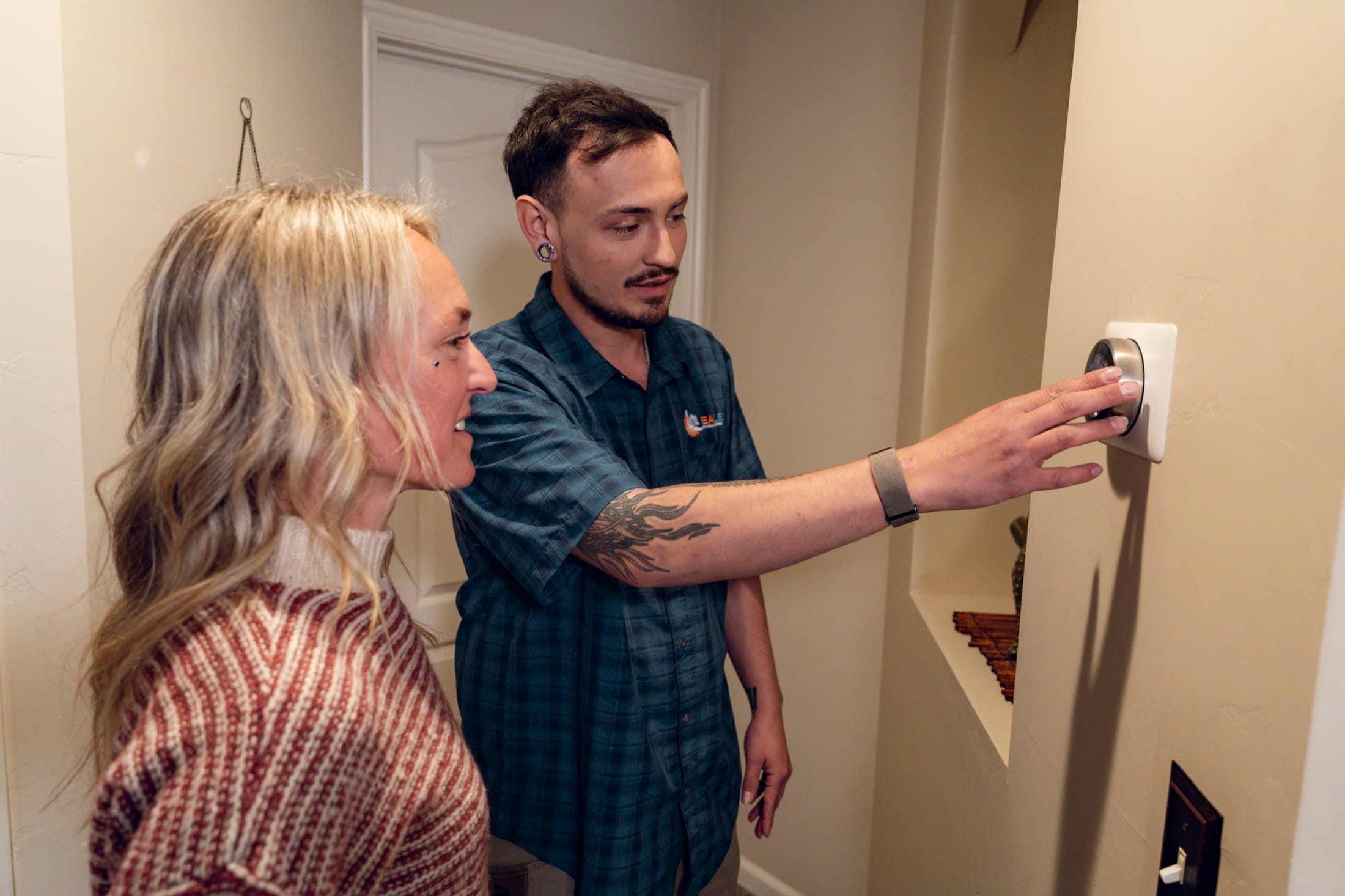 Eagle Heating and Air technician showing a homeowner how to use a smart thermostat